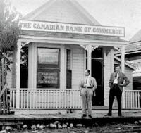 Two men standing in front of the Canadian Bank of Commerce.